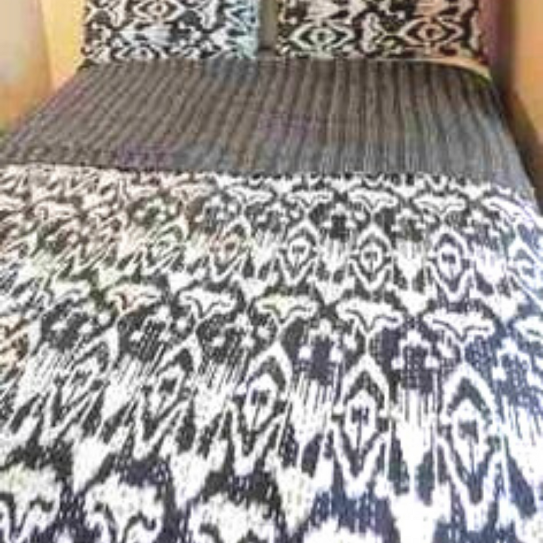 Kantha blanket bedspread set with hand-stitched ikat design in black and white on a bed with matching pillows
