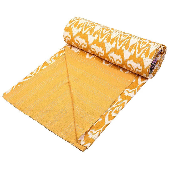 Yellow Ikat design Kantha blanket rolled open showing hand-stitched cotton quilt with reversible solid backing