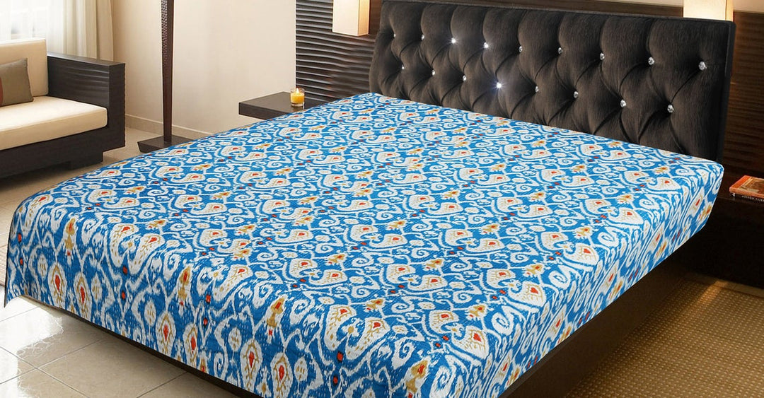 Blue and white ikat design Kantha blanket on king-size bed with tufted black headboard in modern bedroom setting