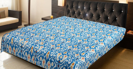 Blue and white ikat design Kantha blanket on king-size bed with tufted black headboard in modern bedroom setting