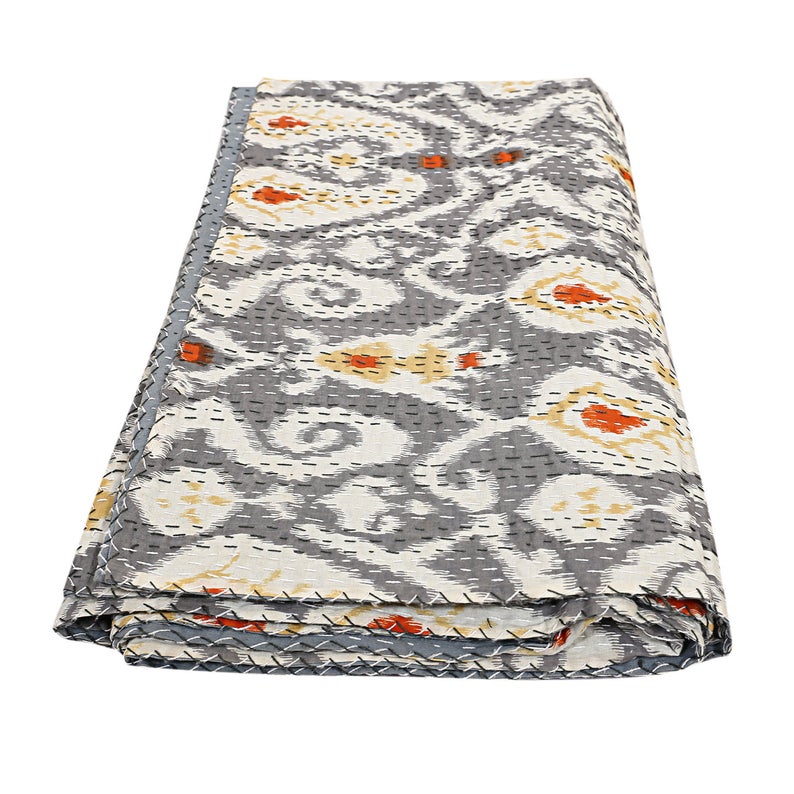 Folded Kantha blanket with hand-stitched ikat design in gray, orange, and yellow colors