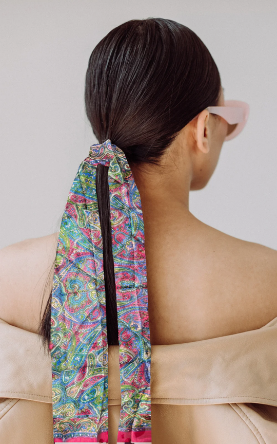Luxurious silk scarf in bright colors, hand-hemmed and lightweight, worn as a hair accessory.