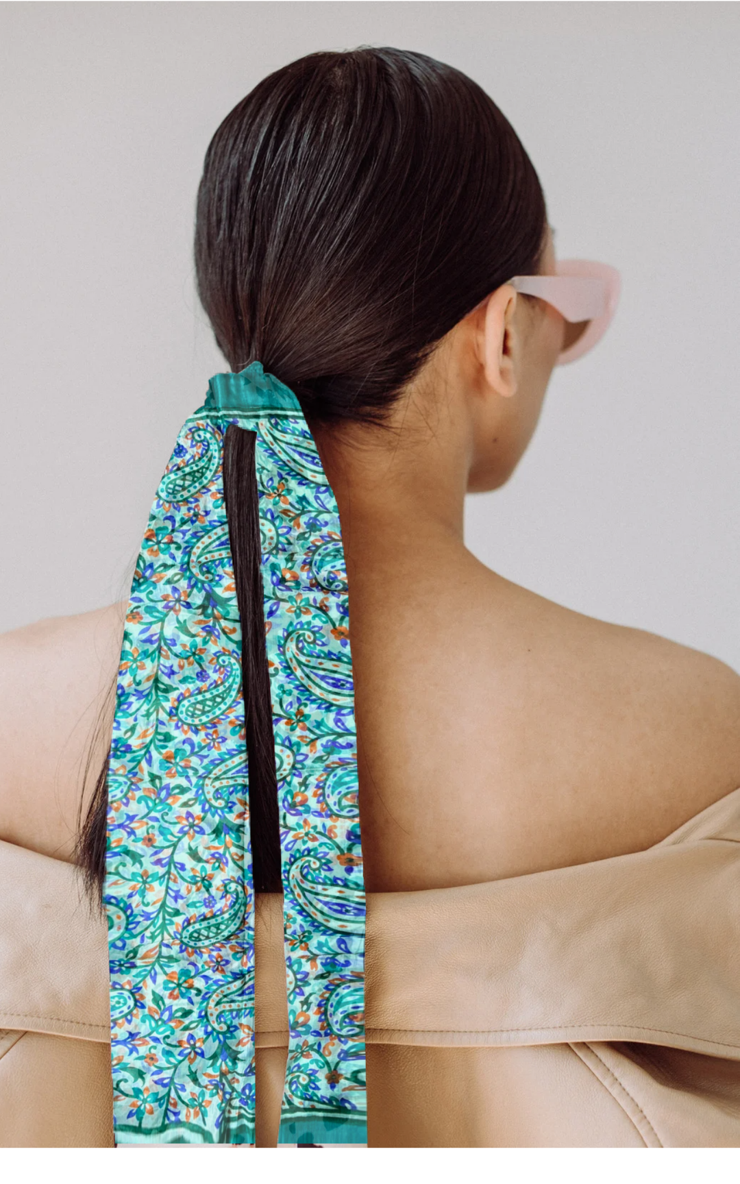 Luxurious hand-hemmed silk scarf in bright colors worn as a hair accessory.