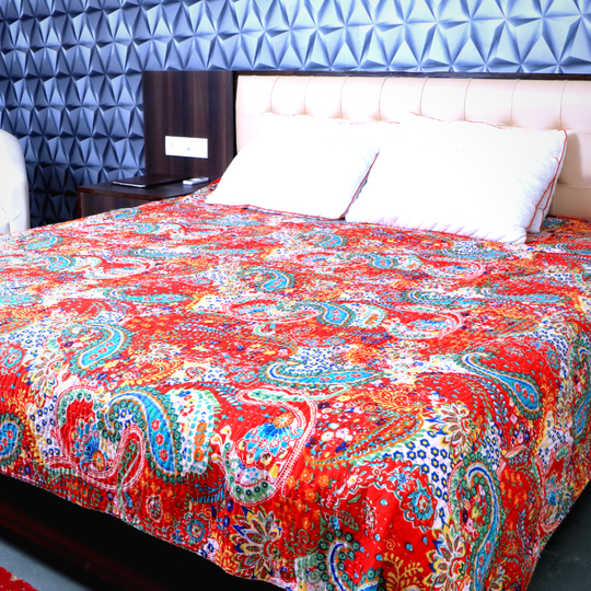 Bright red paisley Kantha blanket set with intricate floral patterns on a bed with white pillows.