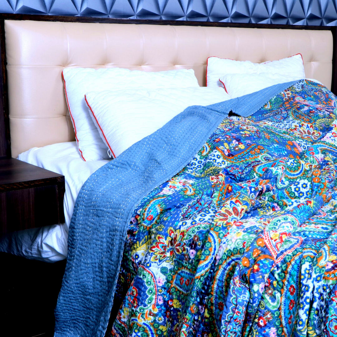 Handmade cotton Kantha blanket set with vibrant paisley design and blue solid backing on bed with white pillows